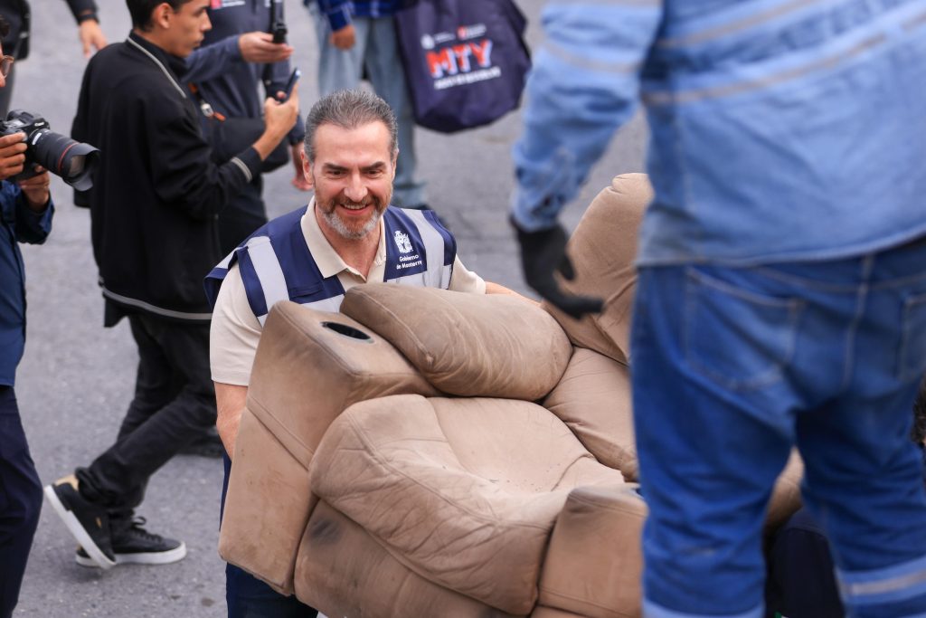 Adrián moviendo un sofá cafe como parte del operativo de limpieza de rescate de espacios en monterrey